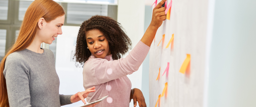 two women working on a white board to show collaboration