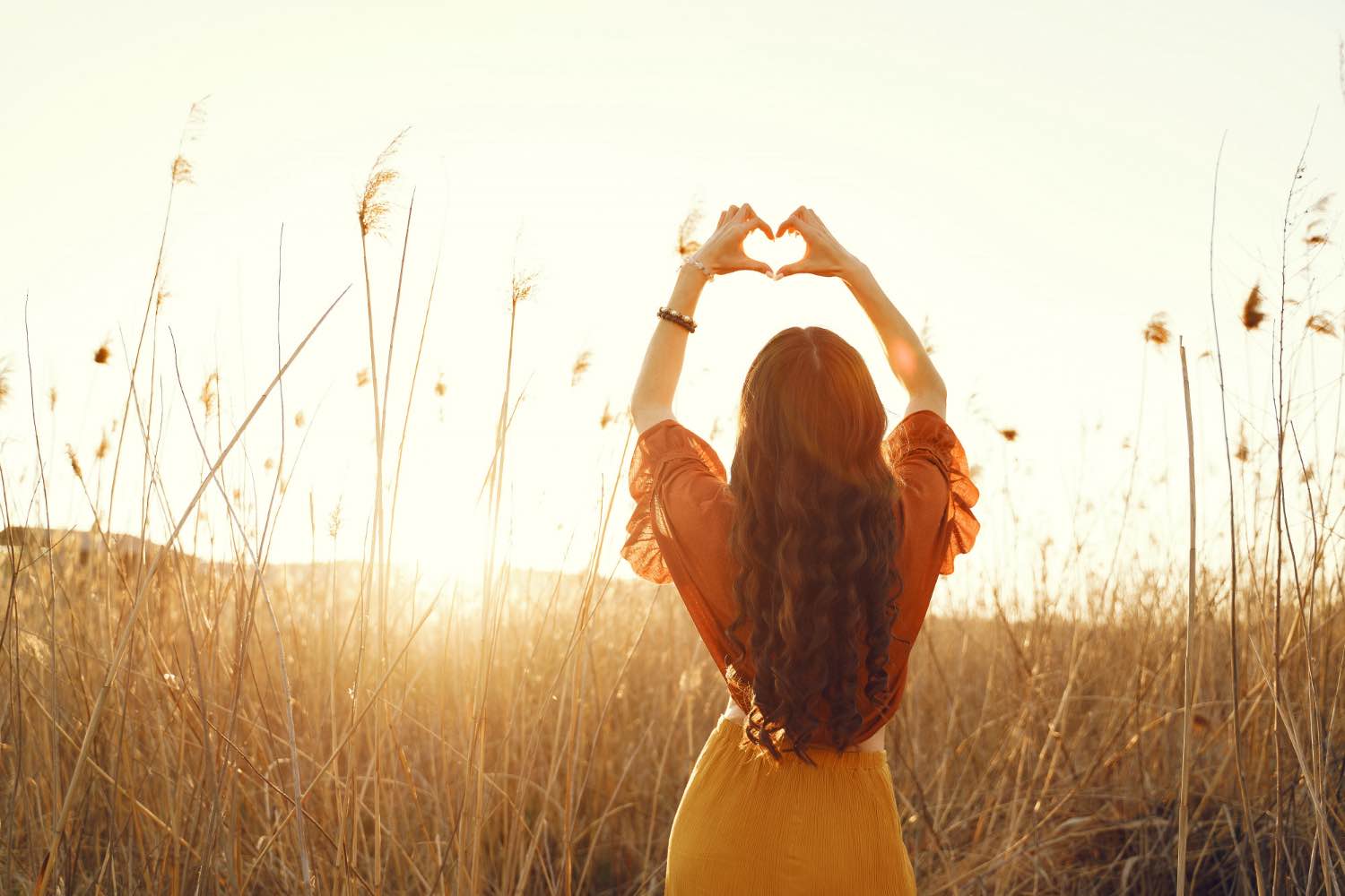 women making a heart into the sun to show love