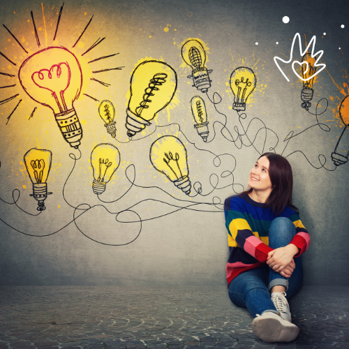 A woman with dark hair is sat on the floor and the wall behind has lightbulbs on it to show her unique ideas and strengths